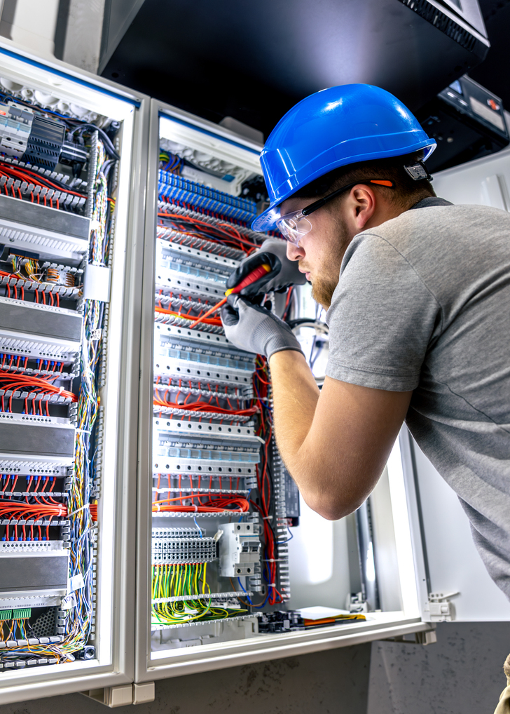 A wide view of a modern industrial control room, with engineers monitoring real-time process control and automation data on multiple screens.