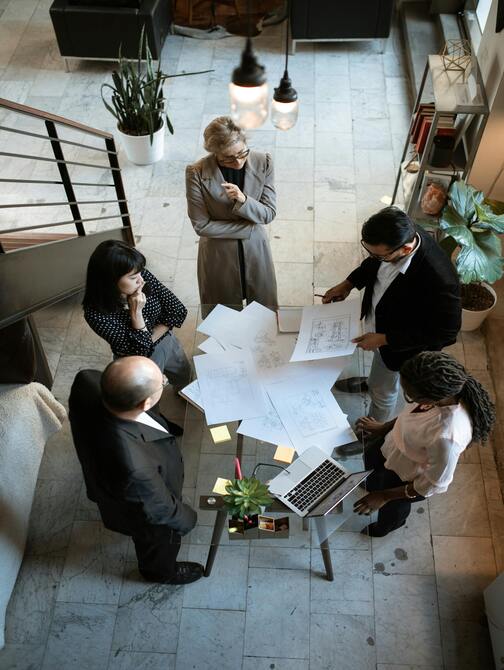 Two project managers or engineers shaking hands over a stack of finalized project documents, symbolizing the completion of a detailed engineering review and sign-off.